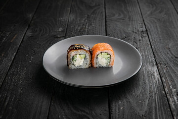 Japanese cuisine. Rolls on a round plate on a black table.
