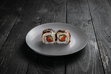 Japanese cuisine. Rolls on a round plate on a black table.
