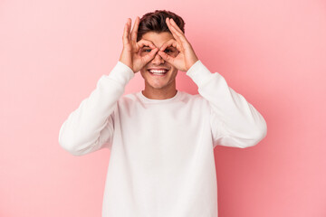 Young caucasian man isolated on pink background excited keeping ok gesture on eye.