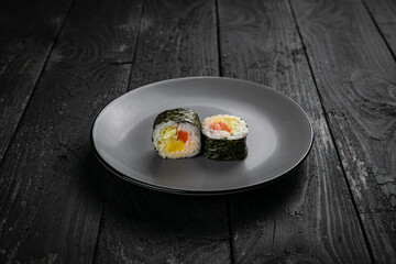 Japanese cuisine. Rolls on a round plate on a black table.
