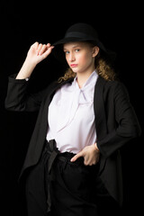 Fototapeta premium Confident girl teenager posing black suit and hat