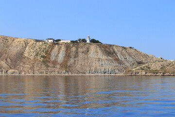 The seashore in sunny weather, a view of the cape and the lighthouse. Suitable for photo wallpapers, photo frames and lovers of water landscapes.