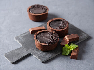 mini chocolate tarts with piece chocolate and mint on a gray  background