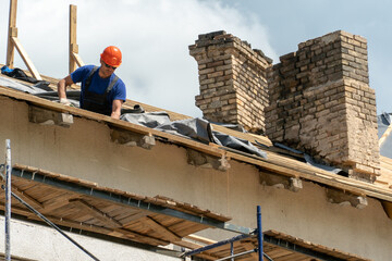 Repair of a wooden roof outdoors on a summer day against the background of blue sky and clouds. A...