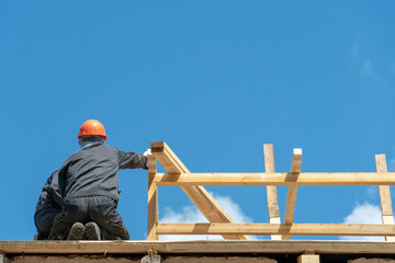Repair of a wooden roof outdoors on a summer day against the background of blue sky and clouds. A...