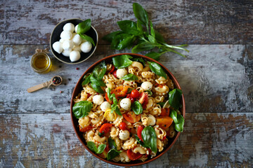 Selective focus. Pasta with tomatoes, basil and mozzarella balls. Italian food.