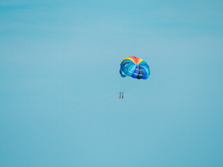 Parasailing with multi colored parachute against blue summer sky. Bulgaria.