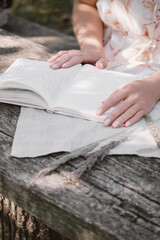 Woman writing, reading diary on the wooden table. Romantic memories. Flipping through notebook, notes outside in park. Memories,