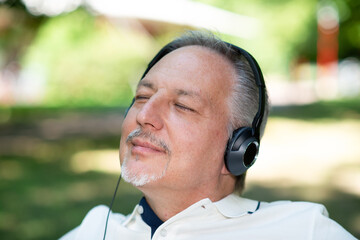 Man listening music in a park with closed eyes