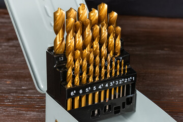 A set of yellow drills in an iron box.
