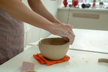Woman hand potter making clay cup in pottery workshop studio. Process of creating ceramic mug. Handmade, hobby art and handicraft concept.