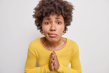 Afro American woman keeps palms pressed together begs for help says please needs something wears...