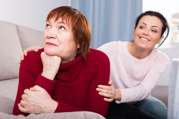 Portrait upset woman looking away after conflict, daughter tries reconcile