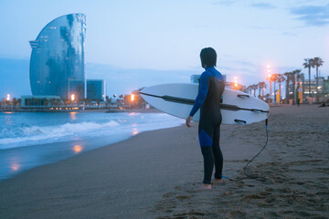From the back silhouette portrait of surfer standing and holding his surf board, ready for surfing...