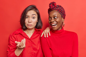 Photo of mixed race diverse women react differently on something stand closely to each other...