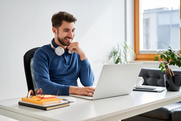 Male student learning on laptop at home sitting at desk