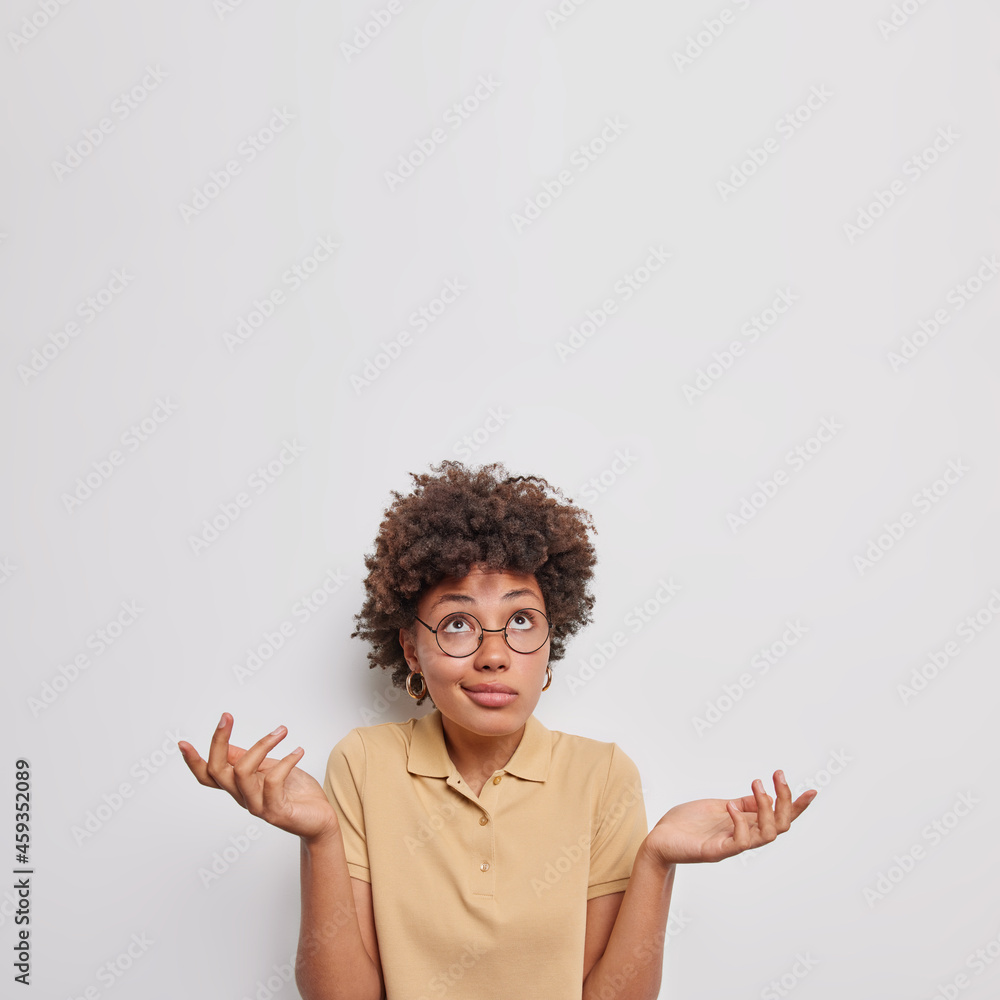 Wall mural indecisive hesitant curly young african american woman spreads palms feels doubtful focused above fe - Wall murals