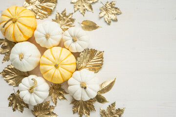 Obraz na płótnie Canvas Sweet mini pumpkins and golden autumn leaves on a white wooden background with copy space. Thanksgiving day decor.