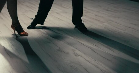 A shot of the dancers' legs, shapely legs of a woman in gold stilettos and black cabaret tights move sexily, gently, nimbly, a girl dancing with a partner in slippers