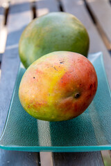 Mangos en una bandeja de cristal sobre una mesa de madera