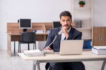 Young male employee sitting at workplace