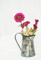 still live with garnet and white dahlias  and chrysanthemums inside a rusty metal jar on a white background, vertical