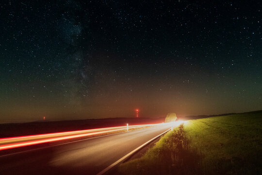 Zu den Sternen, Langzeitbelichtung mit Sternen am Nachthimmel und Lichtspuren von fahrenden Autos, Sternenpark Rh&ouml;n