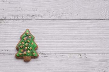 Gingerbread cookie of green Christmas tree on white wood background. Copy space.