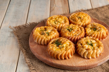 Fresh muffins with vegetables and cheese on wooden board. Delicious homemade cakes for healthy diet. Recipe for autumn seasonal dish.