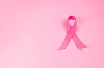 Pink ribbon on colored background. Breast Cancer Awareness Month symbol. Women's health care concept. Promotion of campaign to fight cancer.