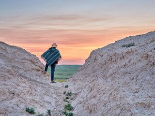 Man in a Mexican poncho and cowboy hat is waiting at dawn for summer sunrise at prairie - Pawnee National Grassland in Colorado