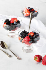 Glass dishes of mixed berries against a white background.