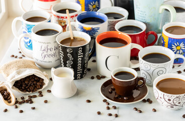A table of many cups of coffee with selective focus on the word coffee on the black cup in front. 