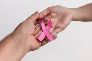 woman hand with pink ribbon and man hand supporting. pink October. breast cancer awareness campaign. selective focus - obrazy, fototapety, plakaty