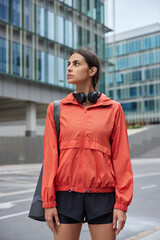 Outdoor shot of young motivated woman in sportswear carries fitness mat trains in morning has workout session poses against blurred city background thinks how to improve health and be active © WHstudio Leushin N