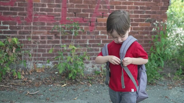 A boy adjusts the strap on his backpack in slow motion