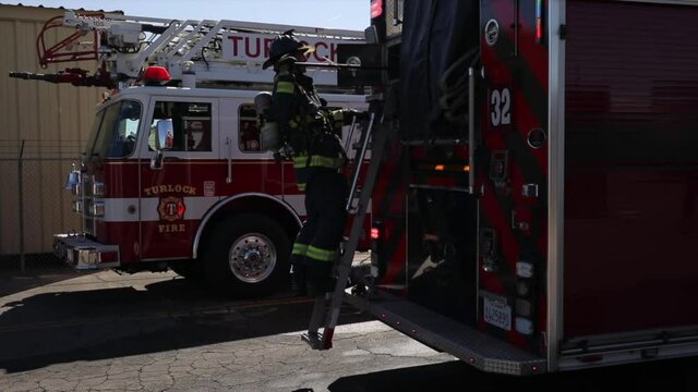 slow motion 60 fps firefighters pulling out equipment from fire trucks in turlock california cali dressed fully with jackets helmets hustling with teamwork epic cinematic midday sunny
