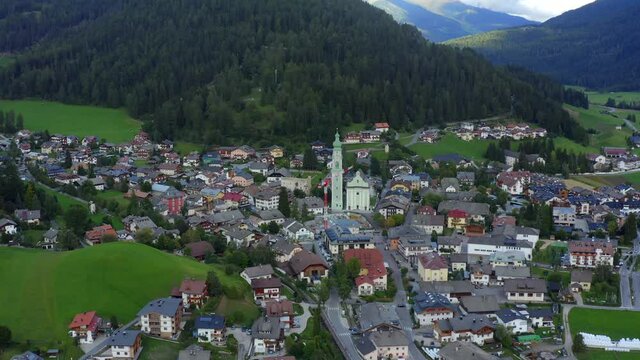 Church of San Giovanni Battista, Dolomites, Toblach, Dobbiaco, Puster Valley, Bolzano, South Tyrol, Italy, September 2021. Drone orbits from the east with the copper roof church in the center.