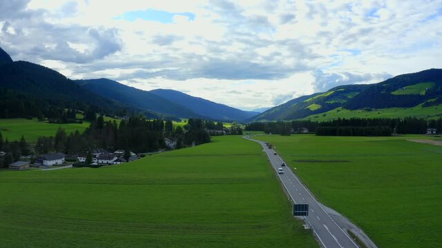 Camping and Villabassa, Dolomites, Puster Valley, Bolzano, South Tyrol, Italy, September 2021. Drone pushes forward following the road west over green fields through the mountainous landscape.
