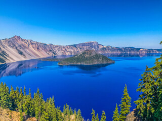 Blue lake in the mountains with large volcanic cinder cone island.