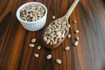 Pinto beans. Carioca beans in a wooden spoon with bowl with  beans on wooden table. Top view. Brazilian culinary.