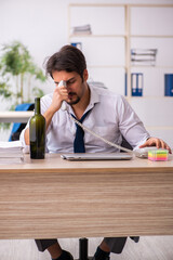 Young alcohol addicted employee sitting in the office