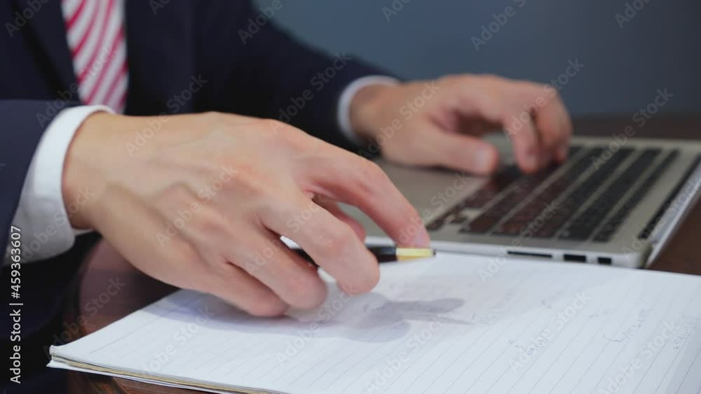 Poster close-up hands of businessman typing keyboard on laptop computer and writing on note with pen at mod