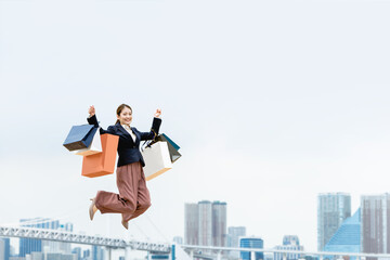 Fototapeta na wymiar 買い物袋を沢山持ってジャンプする女性（セール・爆買い）