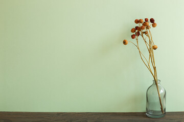 Vase of dry flowers on wooden table. green wall background