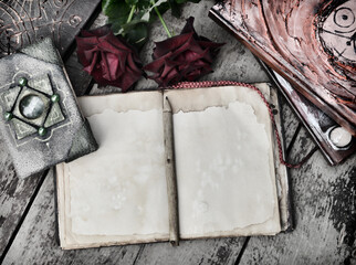 Still life with old book with shabby paper pages, decorated covers and roses on planks.