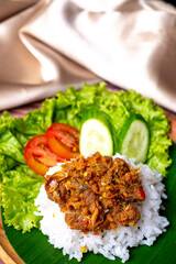 Sambal Peda, Indonesian Traditional Food with white rice, tomatoes, cucumber, and lettuce on wooden plate decorated with golden cloth