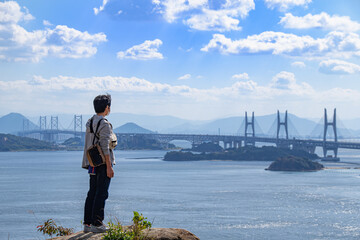 瀬戸大橋を眺める男性の後ろ姿　岡山県倉敷市　An Asian man standing and looking at the view of Seto Ohashi bridge at Setonaikai, Inland Sea of Japan, in Kurashiki city, Okayama pref. Japan 