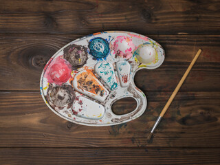 An artist's palette and a brush on a wooden table. Flat lay.