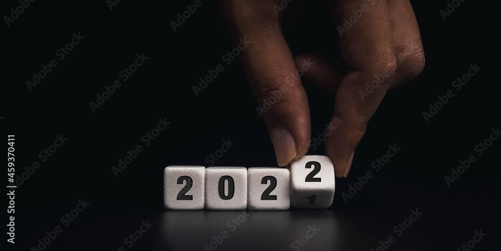 Aufkleber happy new year banner. the year 2021 change to the 2022 concept. close-up hand flipping white dice b